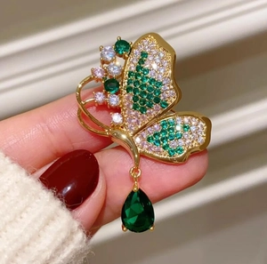 Dettaglio della spilla a farfalla color smeraldo con pendente a goccia verde