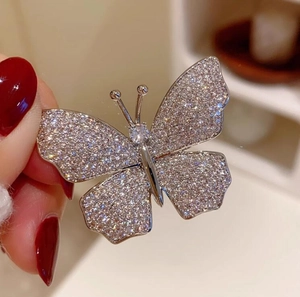 Detailed macro view of a vintage French butterfly brooch with sparkling crystals and silver plating