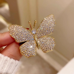 Detailed close-up of a golden butterfly brooch with sparkling crystals and a center stone