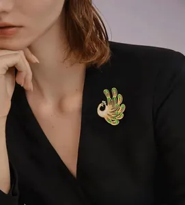 Detailed view of luxury phoenix brooch with emerald crystals on black blazer lapel