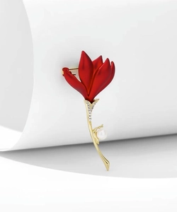 Détail d'une broche fleur rouge mat avec incrustations de cristaux et pendentif perle