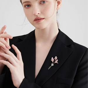 Broche fleur de lys élégante en or rose avec cristaux blancs sur une veste de costume noire