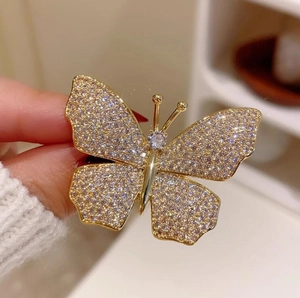 Exquisite gold butterfly brooch with shimmering rhinestones held in a hand for scale
