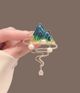 Macro detail of landscape brooch with blue enamel, pearls, and a pink zircon drop