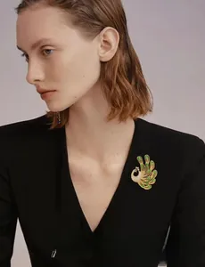 Macro detail of emerald green crystals and rhinestones on gold peacock brooch pin