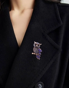 Detail of luxury blue rhinestone owl brooch pinned on black wool coat lapel