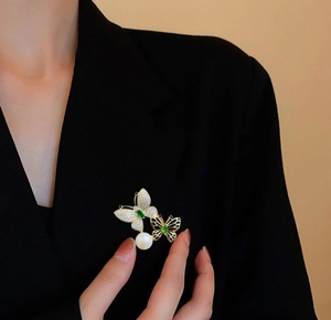 Detailaufnahme der Smaragd-Schmetterlingsbrosche mit Diamanten und Perle auf einem Anzug