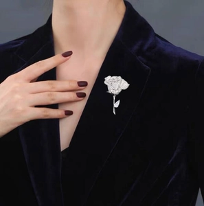 Close-up of sparkling full-diamond rose brooch pinned on a navy blue velvet blazer