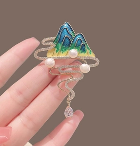Detail of artistic landscape brooch with enamel mountains, pearls and a zircon pendant