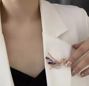 Détail d'une broche dorée élégante avec cristaux violets sur un blazer blanc chic