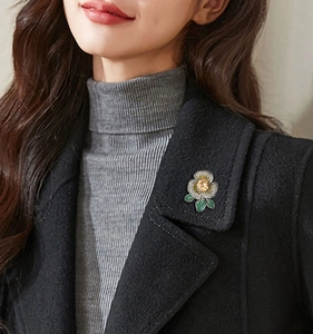 Vue détaillée d'une broche camélia élégante avec strass sur le revers d'un manteau