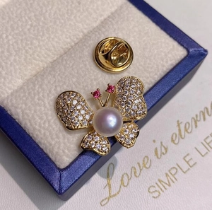 Vue détaillée d'une élégante broche papillon dorée avec perles et cristaux incrustés
