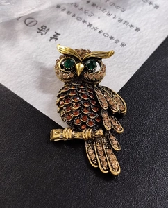 Macro shot of vintage gold owl brooch with emerald eyes and amber crystal detail