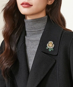 Détail de la broche camélia avec pierre ambre et cristaux blancs sur manteau de laine