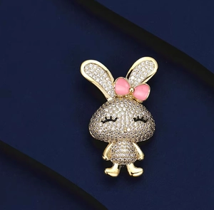 Vue détaillée d'une broche lapin dorée ornée de cristaux et d'un petit nœud rose