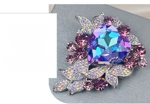 Detail of heart-shaped crystal brooch with gradient purple and teal facets on silver