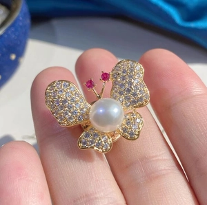Vue détaillée d'une broche papillon dorée ornée de zircons brillants et d'une perle