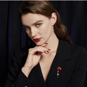 Élégante broche fleur rouge avec tige dorée et perle blanche sur revers de veste