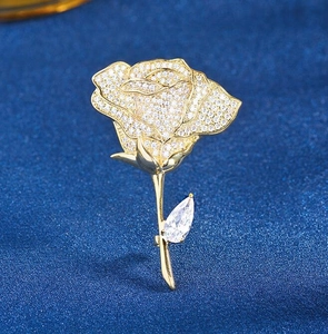 Detailed macro view of a gold rose brooch with sparkling crystals and a teardrop leaf