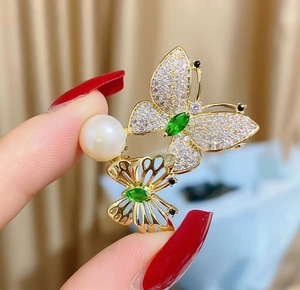 Nahaufnahme der grünen Schmetterlingsbrosche mit Zirkonia-Besatz und einer weißen Perle