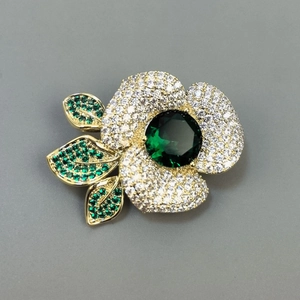 Broche camélia dorée élégante avec cristaux verts et pétales en zircon blanc