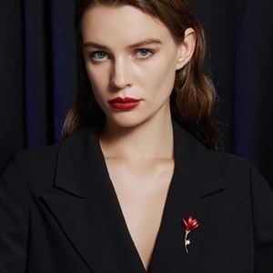Élégante broche fleur rouge avec perle blanche sur revers de veste noire femme