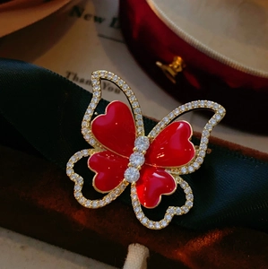 Close-up of elegant red heart enamel butterfly brooch with sparkling zircon and gold metal