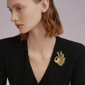 Elegant emerald green crystal phoenix brooch with gold tone stones on black blazer