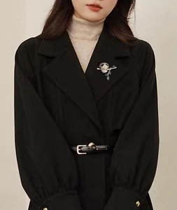 Gros plan détaillé d'une broche panda sur un manteau noir avec branches dorées et cristaux