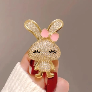 Charmante broche lapin dorée ornée de cristaux scintillants et d'un petit nœud rose