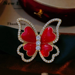 Close-up of elegant red butterfly brooch with shimmering zircons on dark green ribbon