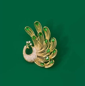 Elegant gold phoenix brooch featuring emerald green crystals and white zircon accents