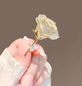 Macro shot of rose brooch with cubic zirconia crystals in gold plating on palm