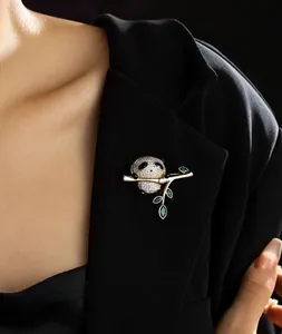 Détail d'une broche panda en cristaux tenant un bambou doré sur un costume noir chic