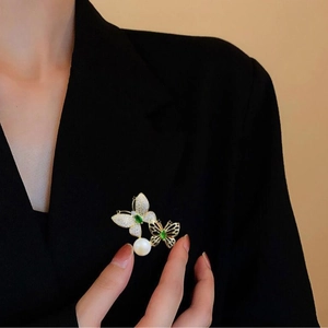 Elegante goldene Doppelschmetterling-Brosche mit grünen Steinen und Perle an einem Blazer