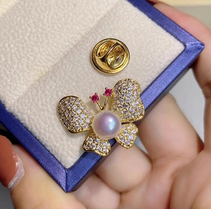 Vue macro d'une broche papillon avec perle violette et strass brillants sur boîte bleue