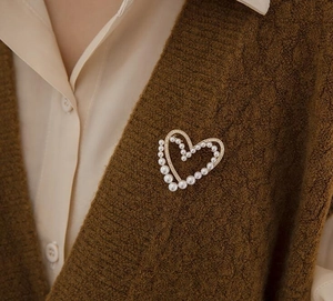 Vue détaillée d'une broche cœur en perles et cristaux sur un pull en maille marron
