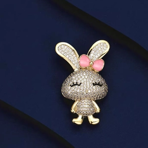 Broche lapin scintillante avec cristaux blancs et nœud rose sur base en métal doré