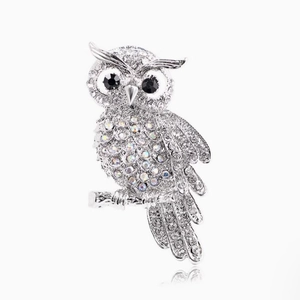 Luxury silver owl brooch with white crystals and black gem eyes on branch with reflection