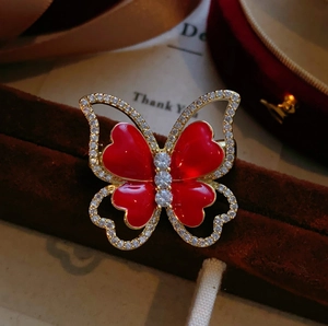 Elegant gold butterfly brooch with red heart wings and zircon inlay on velvet gift box