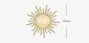 Detail of 36mm sunburst brooch with gold finish, opal center, and sparkling crystals