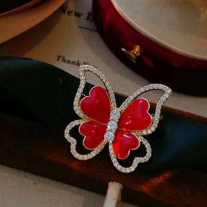 Elegant butterfly brooch with red heart wings and white crystals on green ribbon