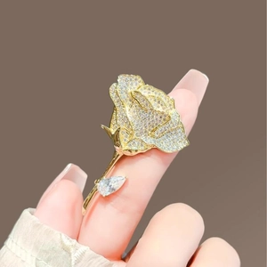 Elegant rose brooch with full crystal pavé and gold finish shown on finger for scale