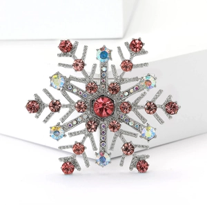 Makroaufnahme der silbernen Schneeflocken-Brosche mit rosa AB-Strass und rotem Stein