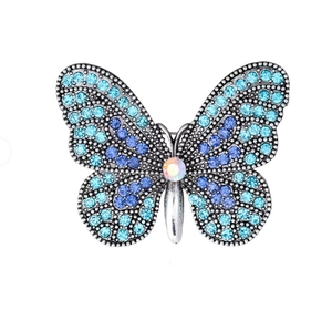 Dettaglio macro di strass blu e viola su una spilla a farfalla in argento lucido