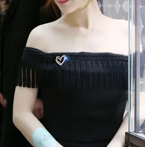 Détail d'une élégante broche en forme de cœur avec perles sur une robe noire
