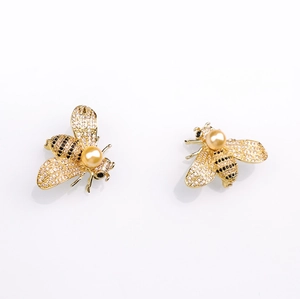 Detailed close-up of luxury bee brooch featuring golden pearls and pave-set zircons