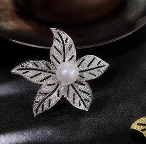 Gros plan détaillé d'une broche fleur à cinq pétales argentée avec perle et zircons