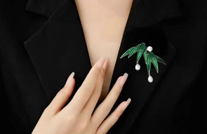 Close-up of elegant bamboo leaf brooch with white pearls on a black suit jacket