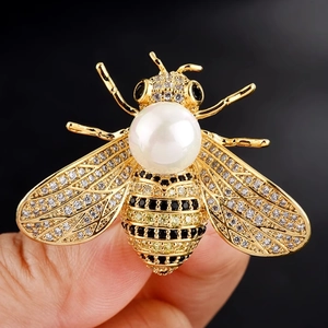 Detailed view of a gold bee brooch featuring a large pearl and sparkling zircon wings
